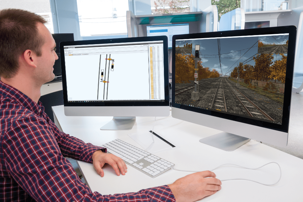 Instructor designing a railway simulation scenario using the Scenario Editor Tool on dual monitors, showing signal configuration and 3D preview.